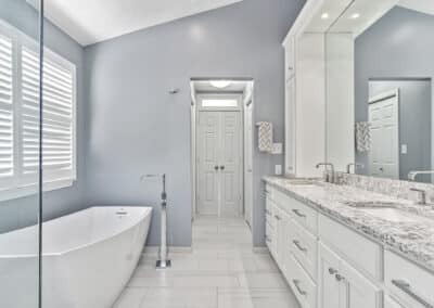 Large master bathroom with free-standing tub on left and large full-width double bowl vanity sink with quartz countertops on right.