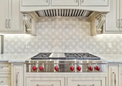 View of luxury kitchen remodel with creamy painted inset cabinets with pro-style Wolf cooktop.
