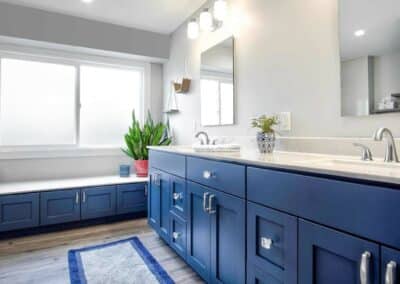 Double sink vanity with custom blue cabinets and light countertop.