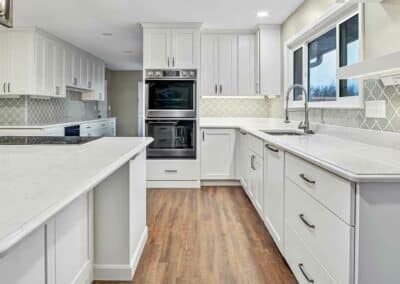 Large kitchen with custom cabinets everywhere. White quartz countertops and fun backsplash pattern in light green hue.