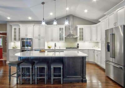 Kitchen remodel with white perimeter cabinets and dark stained island cabinets all with white large vein quartz countertops.