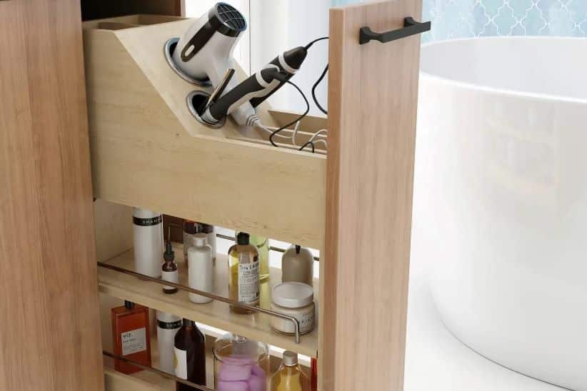 Thompson Price bathroom cabinet storage and organizers showing a pull-out storage unit holding a hair-dryer, straightener and various bathroom cosmetics