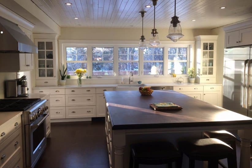 Transitional cabinet styles in st louis showing white shaker frameless cabinetry with glass doors and decorative legs on the island