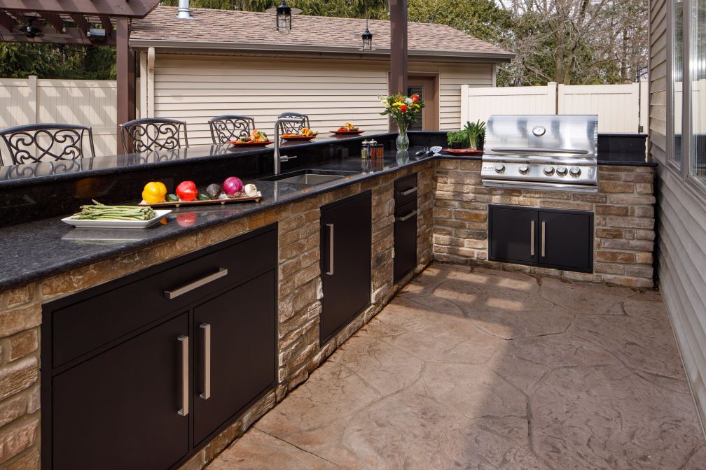 Outdoor kitchen with aluminum black inserts and stainless grill.