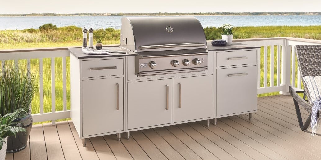 Thompson Price outdoor kitchen cabinets in white aluminum finish shown on deck with large lake in background.