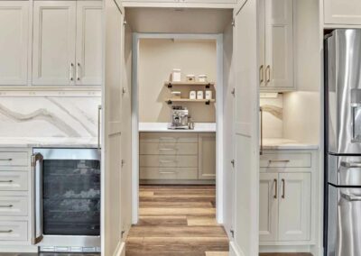 Thompson Price custom kitchen cabinets with hidden pantry entrance in shaker off-white color.