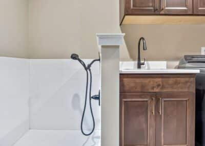 Thompson Price custom laundry room cabinetry in dark stain with custom tile dog shower installed on other side of wall