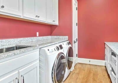 Thompson Price custom laundry room cabinets in white with granite countertops