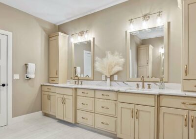 Thompson Price custom tan painted bathroom cabinets with double sink and cabinet storage on the countertops.