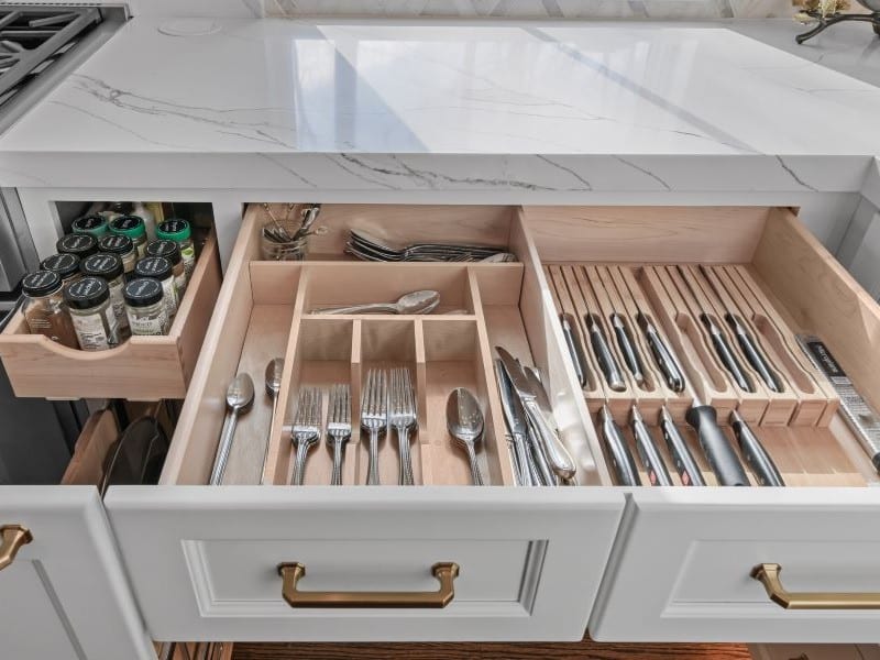 A view of several open cabinet doors and drawers with cutlery dividers and custom storage options