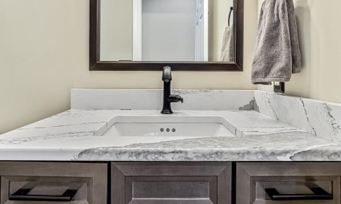 Bathroom remodel with custom stone bathroom countertop over dark stained bathroom cabinets