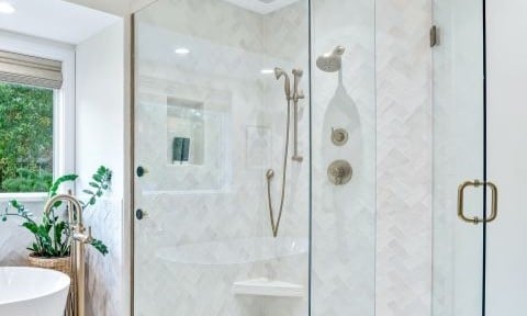 Bathroom remodel showing shower enclosure with ceramic tile walls and champagne bronze plumbing fixtures