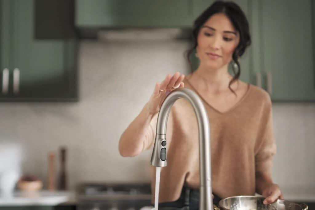 Kitchen and bathroom design trends 2025 showing a woman using a kitchen faucet with smart technology integration