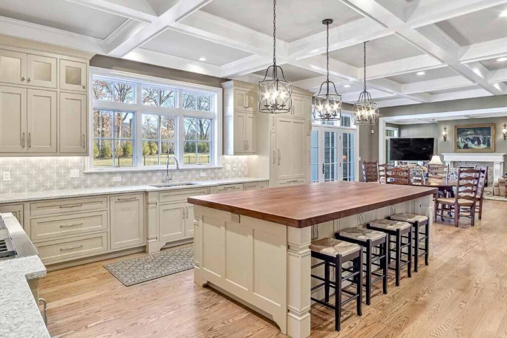 large kitchen remodel with creamy painted custom cabinets with modern door style and vintage lighting and wood countertop on the island