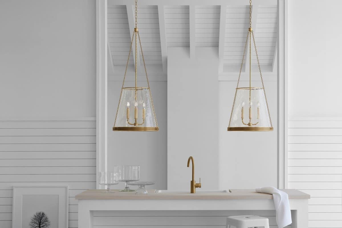 Kitchen island with sink and bronze faucet with decorative large pendant lights above