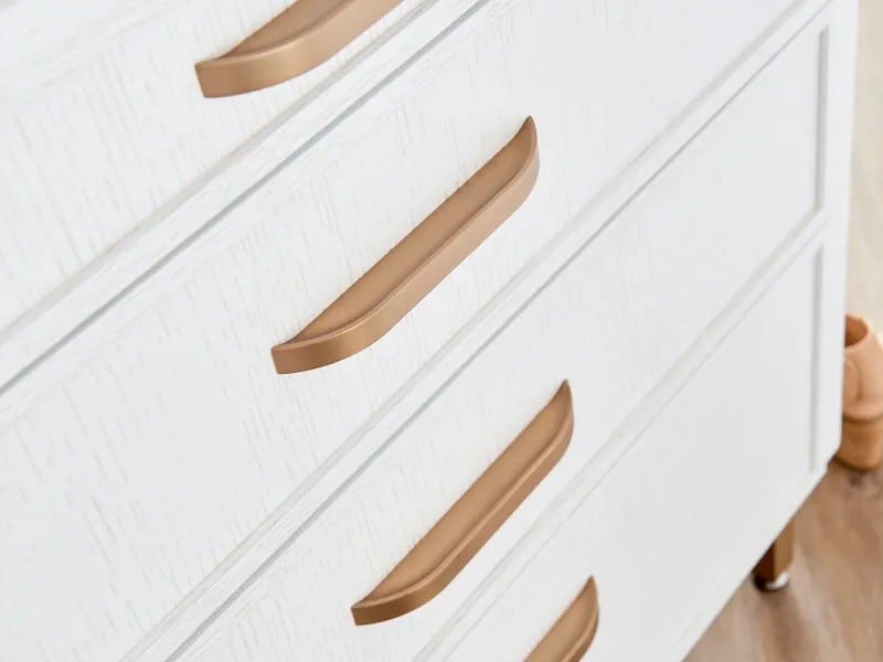 Flat cabinet pulls with rounded corners in satin bronze finish on white painted cabinets